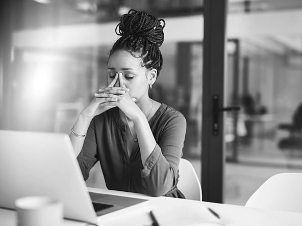 black and white photograph of woman sitting at desk with her face in her hands